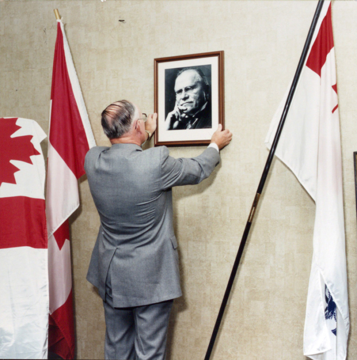 Nigel Brodeur plaçant une photo de son grand-père Louis Philippe Brodeur lors de l'ouverture de la salle Brodeur originale au CFC de Toronto.